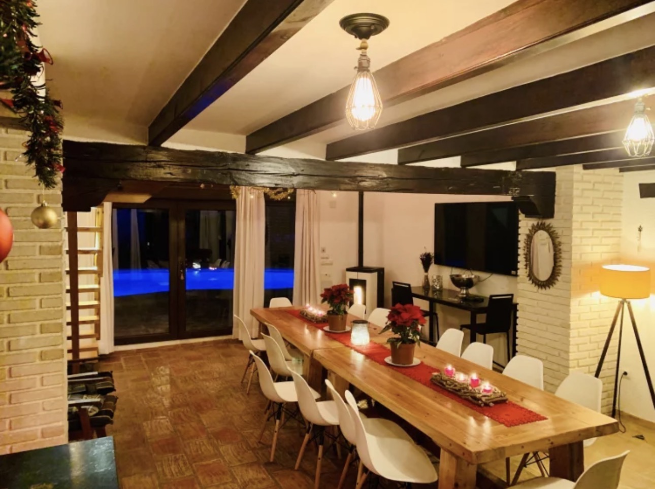 Comedor con mesa grande de madera y vistas a la piscina